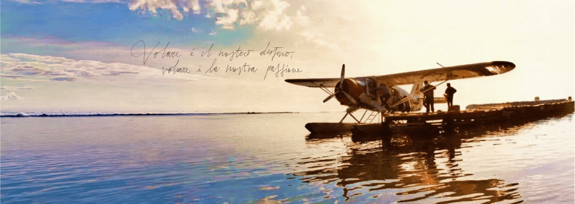 Idrovolante d'epoca ormeggiato al molo al tramonto, con la scritta: Volare è il nostro destino, volare è la nostra passione.